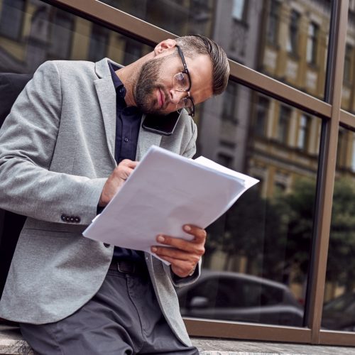 business-communications-young-businessman-standing-leaning-on-wall-on-the-city-street-talking-on.jpg