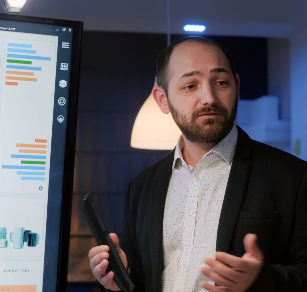 businessman-presenting-management-statistics-using-presentation-monitor-late-at-night.jpg
